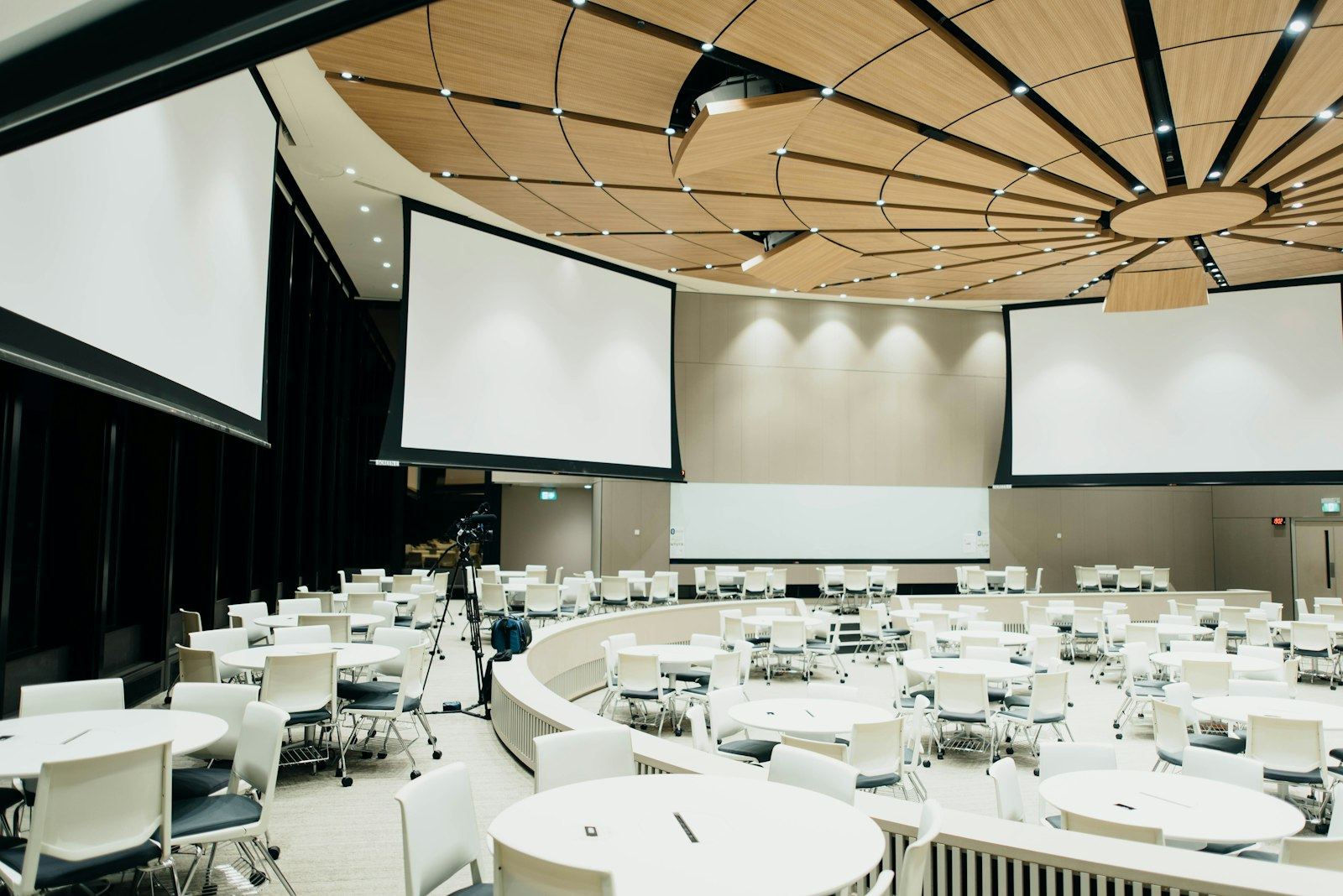 A prepared conference hall with round tables and projection screens